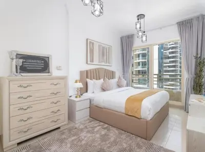 a bedroom with a bed and a dresser and a window at Dubai Marina-short stay in Dubai