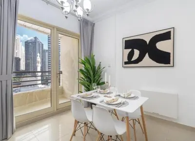 a white dining room with a white table and chairs at Dubai Marina-short stay in Dubai