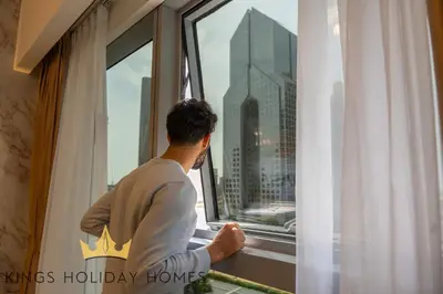 a man looking out of a window at a city at Central Park towers Difc Royal suite kings in Dubai