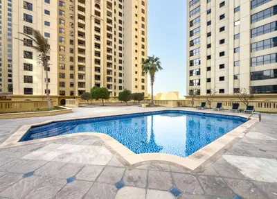 a swimming pool in the middle of two tall buildings at Dubai Eye and Sunset Views 1 Bedroom Apartment with Direct Beach Access, Gym, and Pool in Dubai