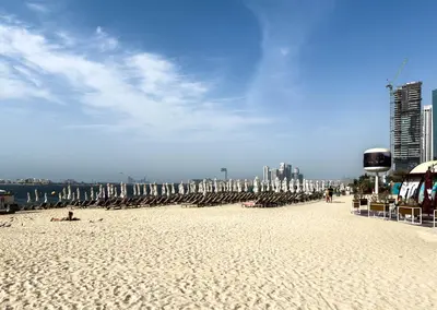 a beach with chairs and umbrellas and people on it at Dubai Eye and Sunset Views 1 Bedroom Apartment with Direct Beach Access, Gym, and Pool in Dubai