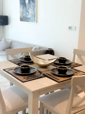 a wooden table with four place settings on it at INA HOMES - Burj Royal 1 BR Stylish Apartment in Dubai