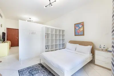 a bedroom with a white bed with white shelves at ALiving Cozy Studio with Balcony I Marina Pearl- 407 in Dubai