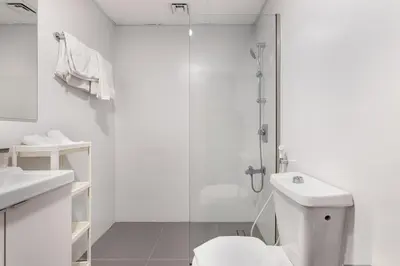a white bathroom with a shower and a toilet at ALiving Cozy Studio with Balcony I Marina Pearl- 407 in Dubai