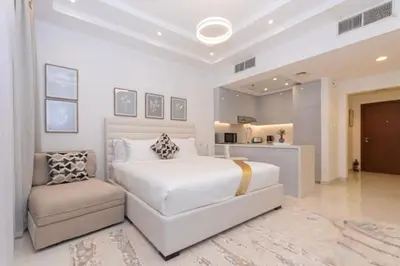 a white bedroom with a bed and a chair at Stylish Studio 5 min Walk to Mall & Burj Khalifa in Dubai