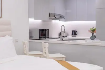 a white kitchen with two chairs and a sink at Stylish Studio 5 min Walk to Mall & Burj Khalifa in Dubai