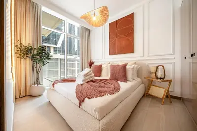 a bedroom with a couch and a large window at Sunset serenity - Urban Oasis Business Bay in Dubai