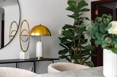 a dining room with a table with a gold lamp and a plant at 1 bedroom Apartment in JBR in Dubai