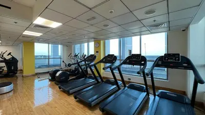a gym with several cardio machines in a room with windows at High floor Marina Views Walk to Beach JBR & Mall in Dubai