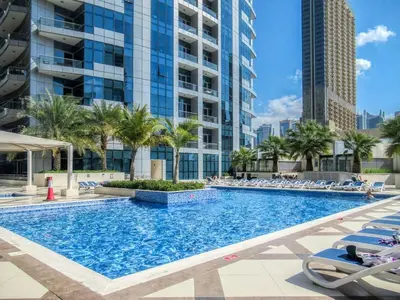 a large swimming pool with chairs and palm trees and buildings at High floor Marina Views Walk to Beach JBR & Mall in Dubai
