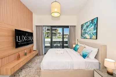 a bedroom with a king sized bed and a tv at Cozy Studio with Balcony in Azizi Riviera and 10 Mins to Burj Khalifa in Dubai