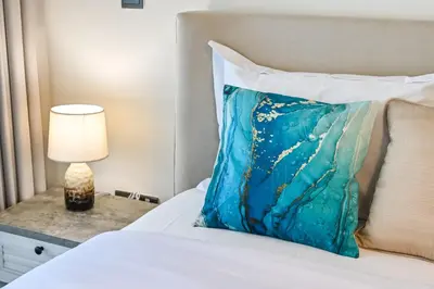a bed with a blue pillow and a lamp on a table at Cozy Studio with Balcony in Azizi Riviera and 10 Mins to Burj Khalifa in Dubai