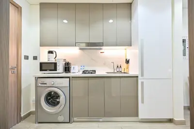 a kitchen with a washing machine and a microwave at Cozy Studio with Balcony in Azizi Riviera and 10 Mins to Burj Khalifa in Dubai