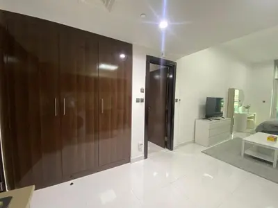 a living room with a large wooden closet and a television at Dubai Silicon Oasis Holiday Homes in Dubai