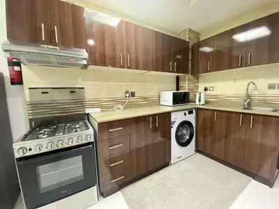 a kitchen with wooden cabinets and a washer and dryer at Dubai Silicon Oasis Holiday Homes in Dubai