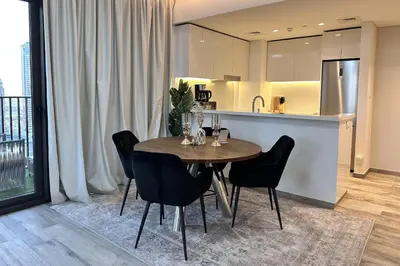 a dining room table with black chairs and a kitchen at Vserve Modern Oasis Canal & Burj Views in Dubai