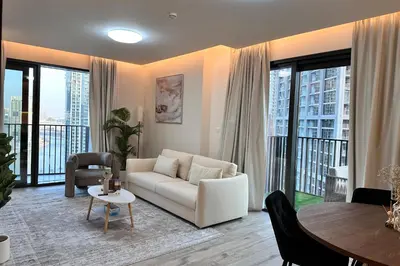 a living room with a white couch and a table at Vserve Modern Oasis Canal & Burj Views in Dubai