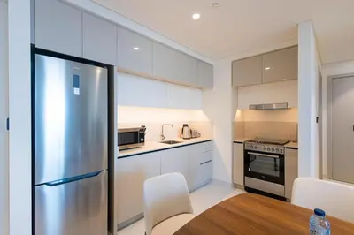 a kitchen with a stainless steel refrigerator and a table at Marina Vista - Elegant 1BR- 2606 in Dubai