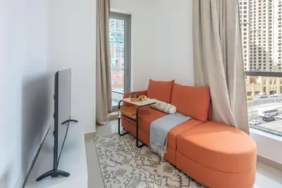 an orange couch in a room with a window at Frank Porter - Bay Central in Dubai