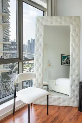 a white bedroom with a mirror and a white chair at Frank Porter - RBC Tower in Dubai