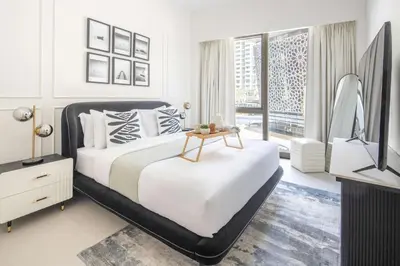 a white bedroom with a bed and a television at Frank Porter - Grande Signature in Dubai