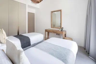 two beds in a white room with a mirror at Frank Porter - Grande Signature in Dubai