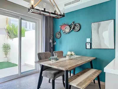 a dining room with a wooden table and a motorcycle on the wall at 3 Bed - Aquilegia, Damac 2 in Dubai