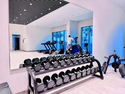 a gym with a row of treadmills and a person in the mirror at Canal Front - Luxury 2BR Stay in Al Wasl in Dubai