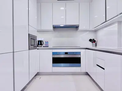 a white kitchen with white cabinets and a blue oven at Canal Front - Luxury 2BR Stay in Al Wasl in Dubai