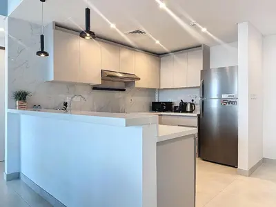 a kitchen with a stainless steel refrigerator and white cabinets at One Residence - Retreat in Dubai