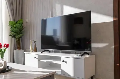 a living room with a tv on a white entertainment center at Stunning Burj View - Cozy 2BR - 5 min Dubai Mall in Dubai