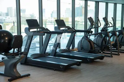 a row of treadmills in a gym with windows at Chic & Serene 1br Apt Balcony, Pool & Parking in Dubai