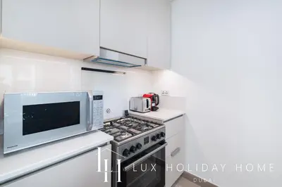 a kitchen with a microwave and a stove at LUX The Dubai Creek Beach Suite in Dubai