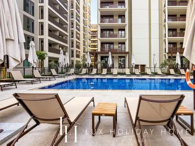a swimming pool with chairs and a table and some buildings at LUX The Dubai Creek Beach Suite in Dubai
