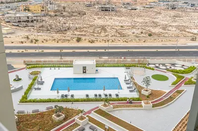 an aerial view of a building with a swimming pool at Stunning 1BR APT in Rukan with Gym and Pool in Dubai