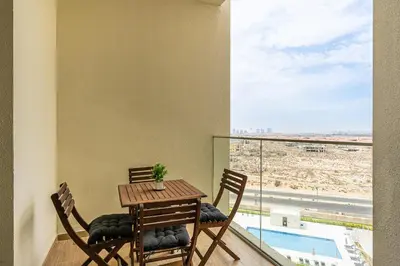 a table and chairs on a balcony with a view of a pool at Stunning 1BR APT in Rukan with Gym and Pool in Dubai
