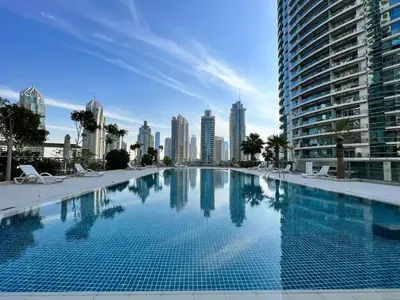 a large swimming pool with a city skyline in the background at Vacay Lettings - Stylish 1 Bedroom Apartment with Marina View, Dubai Marina in Dubai
