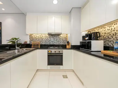 a white kitchen with black and white appliances at Stunning Burj View - High Infinity Pool - Cozy 2BR in Dubai