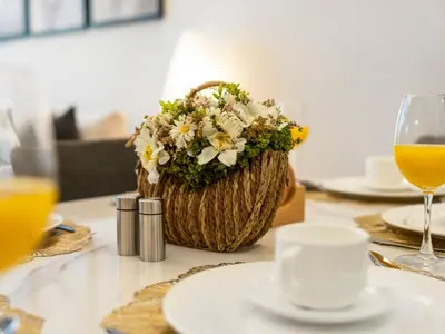 a table with a basket of flowers and a glass of orange juice at Stunning Burj View - High Infinity Pool - Cozy 2BR in Dubai