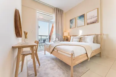 a bedroom with a bed and a table and a window at Steps from Retail Stores and Sports Facilities 1BR, Binghatti Gateway, Al Jaddaf by Deluxe Holiday Homes in Dubai