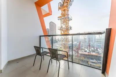 a balcony with two chairs and a crane at Steps from Retail Stores and Sports Facilities 1BR, Binghatti Gateway, Al Jaddaf by Deluxe Holiday Homes in Dubai