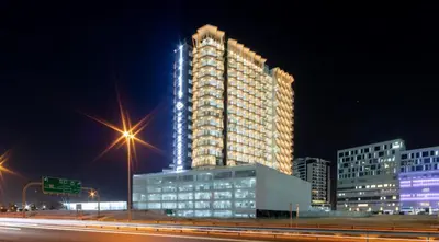 a tall building is lit up at night at Steps from Retail Stores and Sports Facilities 1BR, Binghatti Gateway, Al Jaddaf by Deluxe Holiday Homes in Dubai