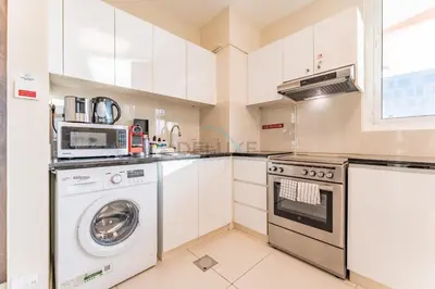 a white kitchen with a washer and dryer at Steps from Retail Stores and Sports Facilities 1BR, Binghatti Gateway, Al Jaddaf by Deluxe Holiday Homes in Dubai