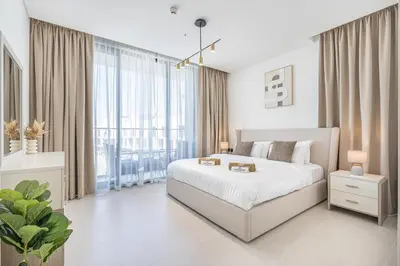 a white bedroom with a bed and a large window at Exquisite Brand New Home in the heart of JVC in Dubai