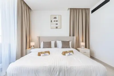 a white bedroom with a large white bed with two pillows at Exquisite Brand New Home in the heart of JVC in Dubai