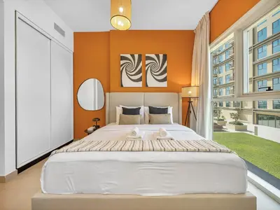 a bedroom with a large bed with an orange wall at Collective Chic 1BR 15mins to Downtown Dubai Mall Beaches in Dubai