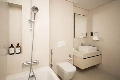 a bathroom with a toilet and a sink and a tub at Seafront-side apartment with beach access, pool, gym, high floor in Dubai