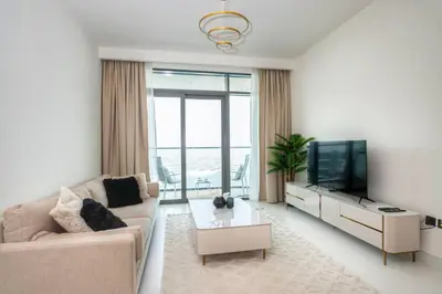 a living room with a couch and a tv at Seafront-side apartment with beach access, pool, gym, high floor in Dubai