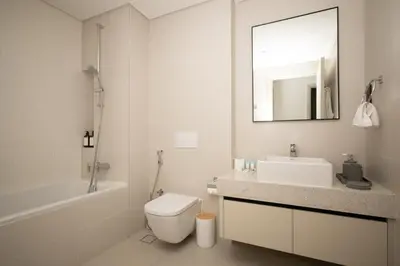a bathroom with a sink and a toilet and a mirror at Seafront-side apartment with beach access, pool, gym, high floor in Dubai