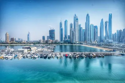 a group of boats in a harbor with a city at Seafront-side apartment with beach access, pool, gym, high floor in Dubai